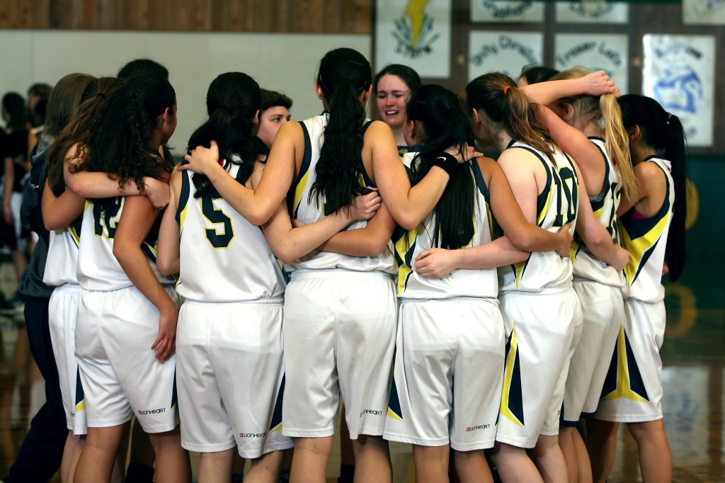 Equipo femenino de chicas jóvenes jugadoras de baloncesto, que están en corro. 